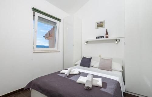 a white bedroom with a bed with towels on it at Holiday apartment Boko in Pinezici