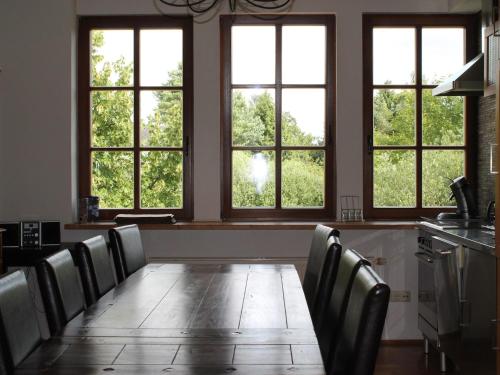 a long table with chairs in a room with windows at Gutshaus in Gressow mit Teich in Gressow