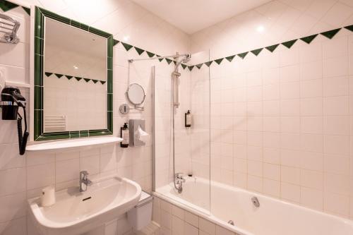 a white bathroom with a sink and a tub and a mirror at Hotel Burrhus in Vaison-la-Romaine