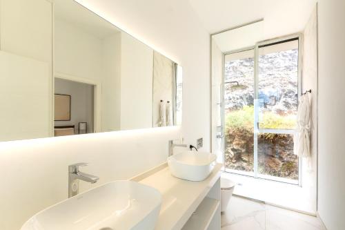 une salle de bain blanche avec un lavabo et une fenêtre dans l'établissement Crystal I Luxury Apartments by Hermosa Rentals, à Acantilado de los Gigantes
