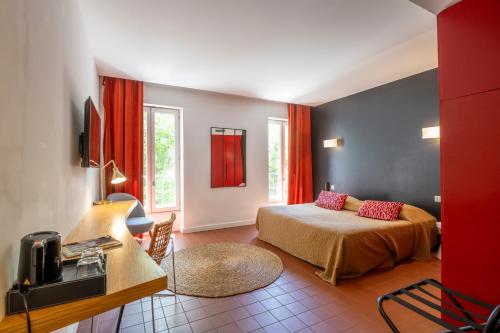 a bedroom with a bed and a table in a room at Hotel Burrhus in Vaison-la-Romaine