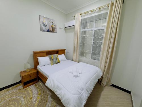 a small bedroom with a bed and a window at Sinza Hiddenout in Dar es Salaam
