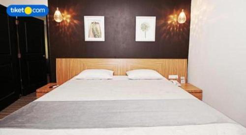 a bedroom with a large white bed with two pillows at Kenari Tower Hotel in Makassar