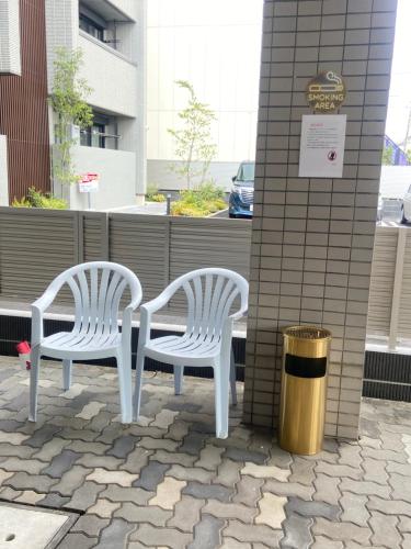 two white chairs sitting next to a building at raikoエレベーター付き大人数向け一棟貸切宿 in Nishi-biwashima