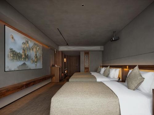 a hotel room with three beds and a painting on the wall at Zhangjiajie SANHE Hotel --Free one way pick up service over 2 night, Free shuttle to east gate of forest park,Free laundry service,Free fresh coffee,English speaking customer service in Zhangjiajie