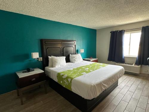 a bedroom with a large bed and a blue wall at Rodeway Inn in Bloomington