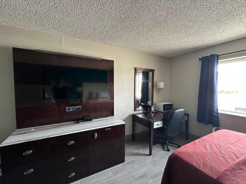 a bedroom with a bed and a dresser and a desk at Rodeway Inn in Bloomington