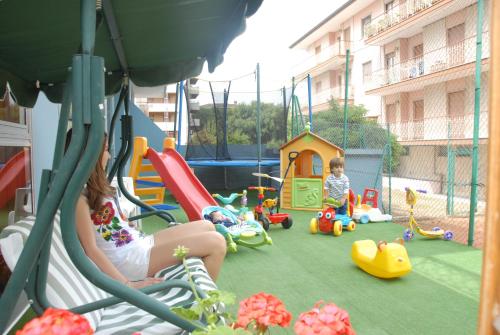 una mujer y un niño jugando en un patio de recreo en Hotel President, en San Benedetto del Tronto