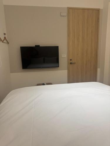 a bedroom with a white bed and a flat screen tv at DayBreak 2 in Taitung City
