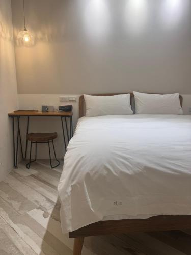 a bedroom with a large white bed and a table at DayBreak 2 in Taitung City