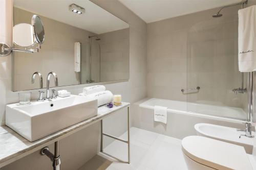a bathroom with a sink and a tub and a toilet at Esplendor by Wyndham Montevideo Cervantes in Montevideo