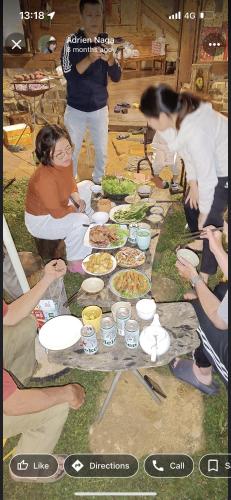 a group of people sitting around a table with food at A Ơi Di Linh homestay 
