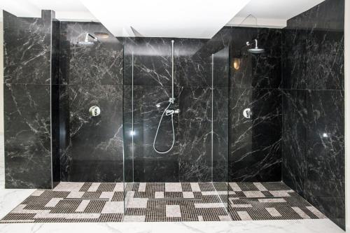 a bathroom with a shower with black marble walls at Haus am Berg in Vartop