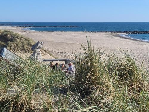 a group of people walking down a sandy beach at Strandhuset in Agger