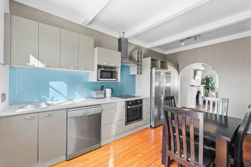 a kitchen with white cabinets and a table and chairs at Central Epsom Retreat in Auckland