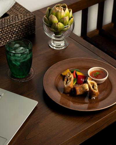 a plate of food on a table with a bowl of fruit at Kirindi Paddy Isle in Negombo