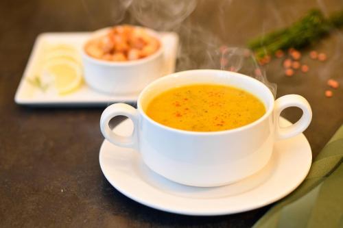 a cup of soup sitting on a plate on a table at Clarion Hotel Jeddah Airport in Jeddah