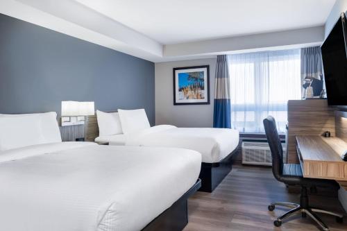 a hotel room with two beds and a desk at Microtel Inn & Suites by Wyndham Kanata Ottawa West in Kanata