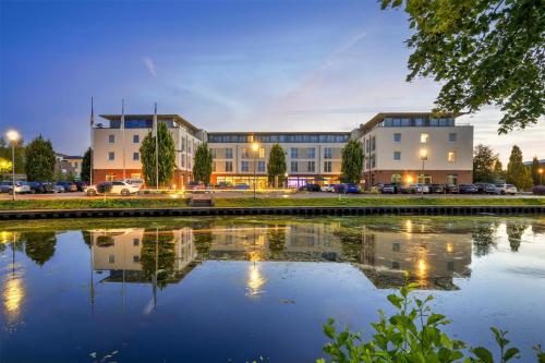 a building with a reflection in a body of water at Best Western Plus Hotel Papenburg in Papenburg