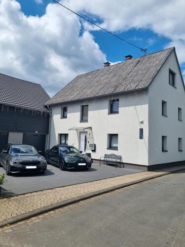 two cars parked in front of a white building at CJS Apartments - Chill or Drive am Nürburgring, Free Parking, WLan, Spacious Rooms, Quiet Location in Rodder