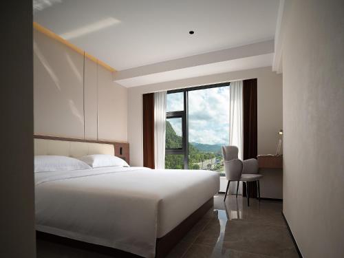 a bedroom with a large white bed and a window at Zhangjiajie SANHE Hotel --Free one way pick up service over 2 night, Free shuttle to east gate of forest park,Free laundry service,Free fresh coffee,English speaking customer service in Zhangjiajie