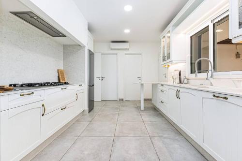 Una cocina blanca con gabinetes blancos y un fregadero. en Quinta dos Figos - Jacuzzi Perto da Praia, en Guia