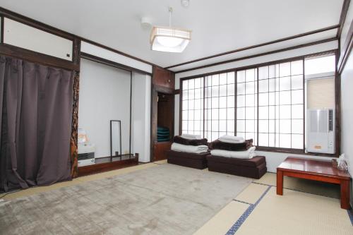 a living room with two couches and large windows at Sansan Yuzawa Backpackers in Yuzawa