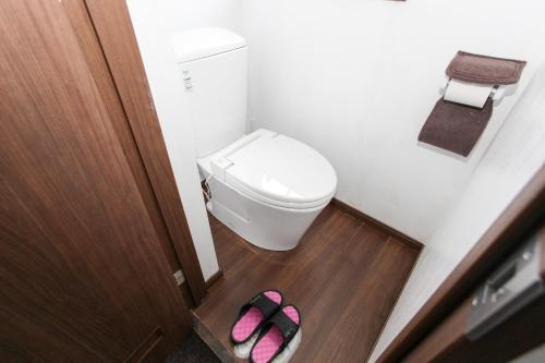 a bathroom with a toilet and a pair of pink slippers at Sansan Yuzawa Backpackers in Yuzawa