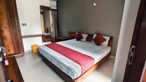 a bedroom with a large bed with red pillows at Nelleri Residency Managed By Vaishno Hospitality in Iritti