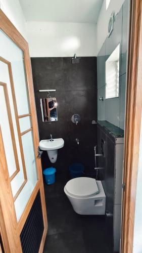 a bathroom with a white toilet and a sink at Nelleri Residency Managed By Vaishno Hospitality in Iritti
