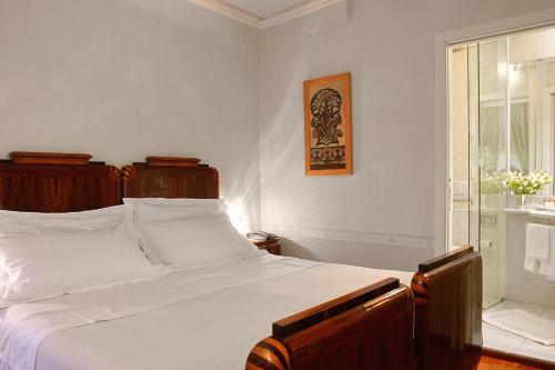 a bedroom with a bed with white sheets and a window at Residenza d'Epoca Campo Regio Relais in Siena
