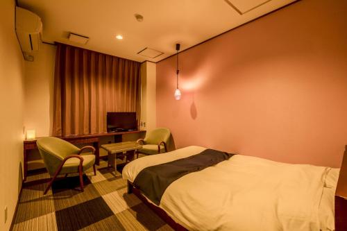 a hotel room with a bed and chairs and a desk at Ooedo Onsen Monogatari Yamanaka Saichoraku in Kaga
