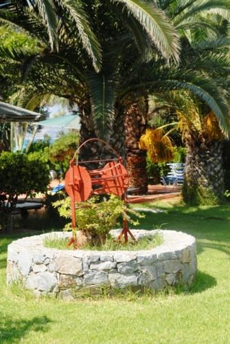 a statue in the grass in front of a palm tree at Kalives Apartments in Kalyves