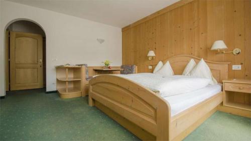 a bedroom with a large bed with a wooden headboard at Hotel Garni Ruscel in Santa Cristina Gherdëina