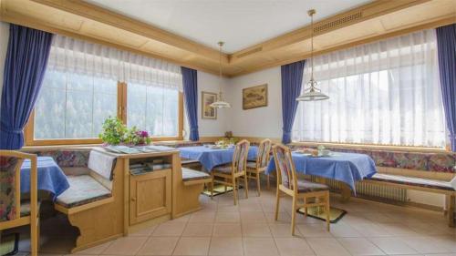 un comedor con mesas y sillas azules y ventanas en Hotel Garni Ruscel, en Santa Cristina Valgardena