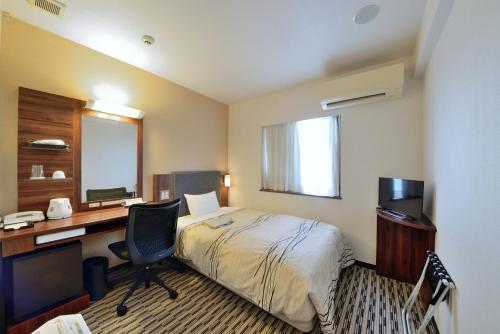 a hotel room with a bed and a desk and a computer at Uozu Manten Hotel Ekimae in Uozu