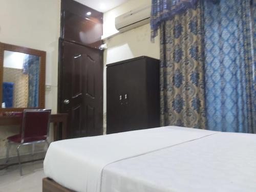 a bedroom with a bed and a chair and a window at Minal Inn Hotel in Lahore
