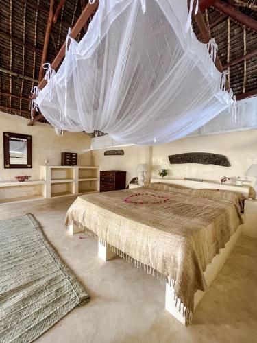 a bedroom with two beds and a mosquito net at La Joya Lamu in Shela