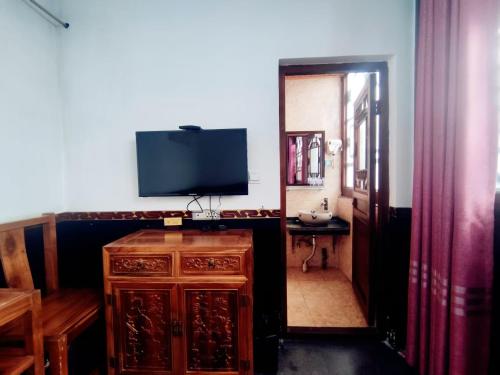 a living room with a television and a wooden cabinet at Pingyao Xiangshengyuan Guest House in Pingyao