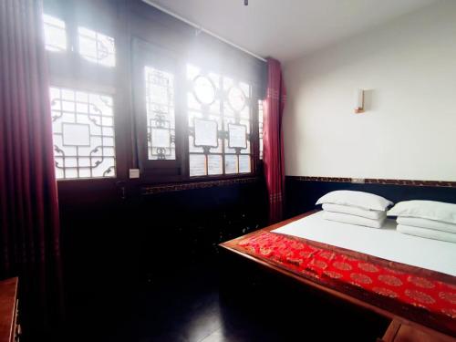 a bedroom with a bed and two windows at Pingyao Xiangshengyuan Guest House in Pingyao