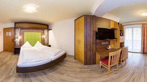 a bedroom with a bed and a desk in a room at Hotel-Pension Egger in Grossarl