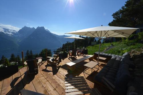 a patio with tables and chairs and an umbrella at Berggasthaus Eggberge - Boutique Mountain Hotel - Access via Cablecar in Altdorf