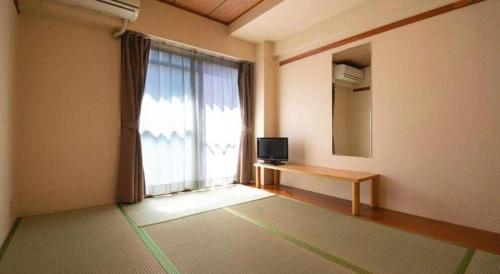 a room with a window with a television and a table at Business Hotel Wako in Ichinomiya