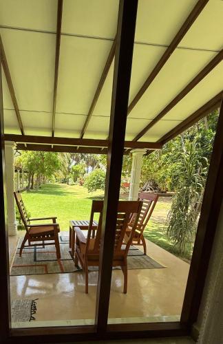 a screened porch with chairs and a table and a bench at 108 Palms Beach Resort in Trincomalee