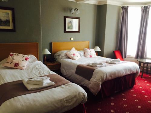 a hotel room with two beds and a red carpet at Plas Coch Hotel Ltd in Bala