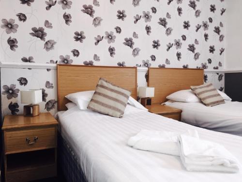two beds in a bedroom with flowers on the wall at Plas Coch Hotel Ltd in Bala