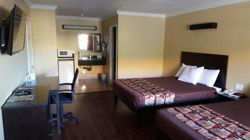 a hotel room with two beds and a desk at Anaheim Astoria Inn & Suites in Anaheim