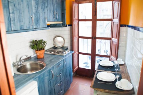 a kitchen with blue cabinets and a sink and a window at Apartamentos de la Parte Antigua de Cáceres in Cáceres