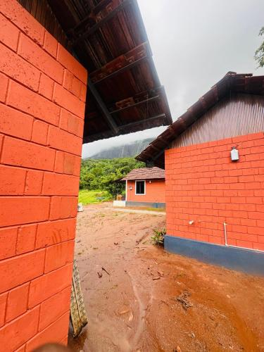 a red brick building next to a dirt field at Jungle Homes in Kollengode