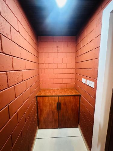 a room with a red brick wall and a wooden cabinet at Jungle Homes in Kollengode